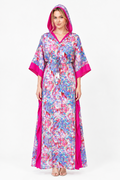 A woman modeling a long hooded kaftan dress with a vibrant blue, pink, and white floral pattern, featuring solid hot pink trim on the sleeves, hem, and side drape, set against a plain white studio background.