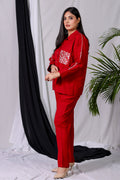 A model wearing a cherry red hand-embroidered co-ord set, consisting of a collared shirt and matching trousers.