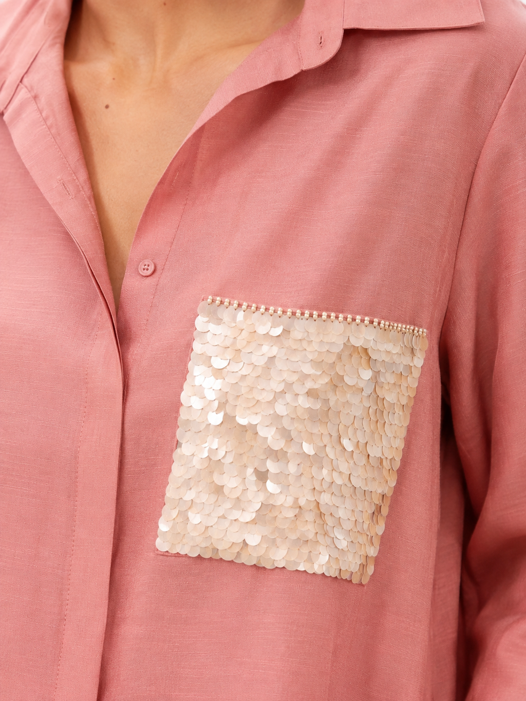 A close-up of a dusty pink button-up shirt featuring a large, square sequined chest pocket in a champagne beige tone.